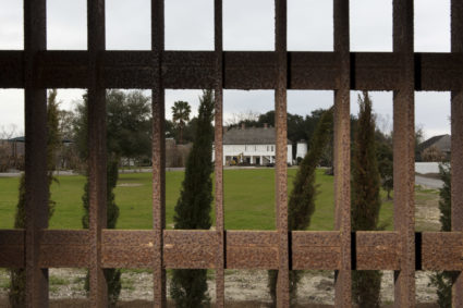 The main house of the Whitney Plantation is seen through the bars of a steel cage used as a jail in Wallace Louisiana