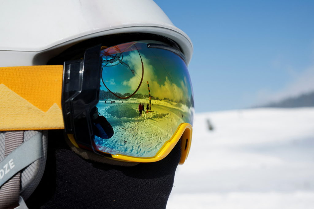 A reflection in ski goggles shows people in a snow-covered field in Gulmarg, a ski resort and one of the main tourist attr...