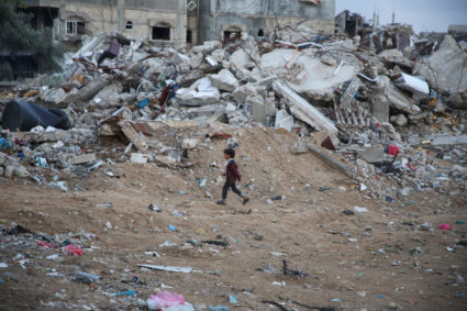A Palestinian child walks past the rubble of a building destroyed during the Israeli offensive, amid a ceasefire between I...