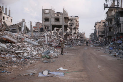 A Palestinian stands by the rubble of buildings destroyed during the Israeli offensive, amid a ceasefire between Israel an...