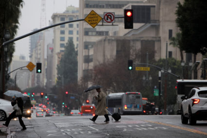 Pedestrians cross a street as it rains in Downtown Los Angeles
