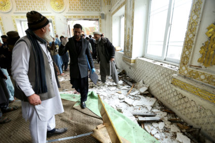 People inspect damage, at the site of a suicide bomber attack, on the day of Friday prayers, at an Islamic seminary in Ako...