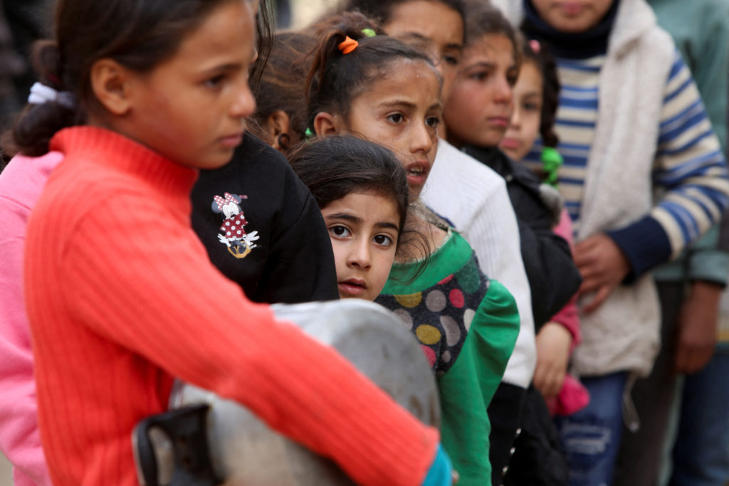 Palestinians gather to receive food cooked by a charity kitchen, in Khan Younis