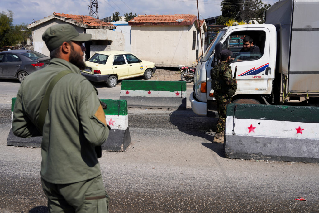 Members of Syrian security forces man a checkpoint at the entrance of Latakia
