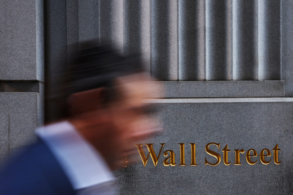A man walks past a Wall Street marking outside the New York Stock Exchange (NYSE) building on Tuesday following Monday’s b...