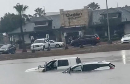 Vehicles are partially submerged in flood waters at a road in McAllen
