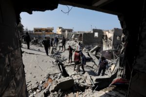 Palestinians inspect the site of an Israeli strike on a residential building, in Deir Al-Balah