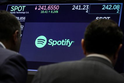 A screen displays the logo and trading information for Spotify on the floor of the NYSE in New York
