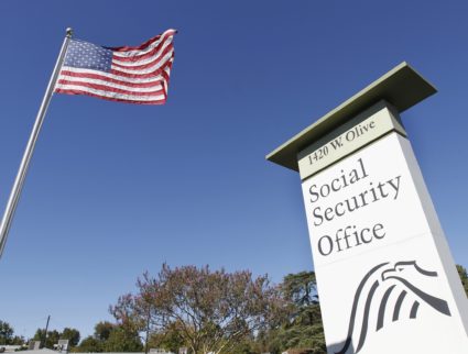 An American flag flutters in the wind next to signage for a U.S. Social Security Administration office in Burbank