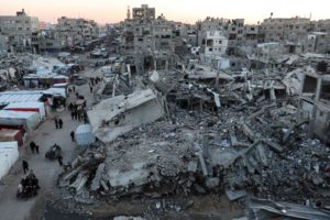 Palestinians walk among the rubble of buildings, In Khan Younis