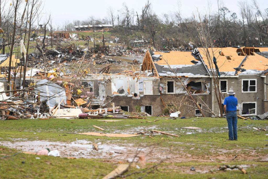 A man looks at debris on the ground after apartments were struck by a tornado in Selmer