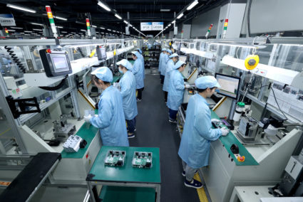 Workers work on a production line manufacturing smart automotive central control navigation products at a factory in Suqian