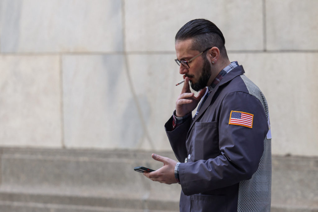 A trader smokes on Wall Street outside the New York Stock Exchange (NYSE) in New York