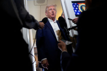 U.S. President Donald Trump speaks to the media on board Air Force One on the way to Palm Beach International Airport