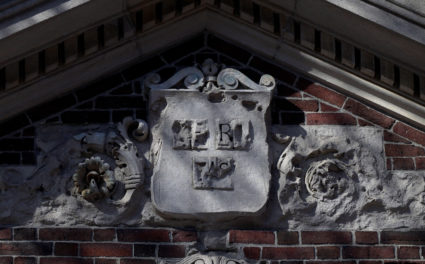 The Harvard University shield "VERITAS" sits above a campus entrance gate at Harvard University in Cambridge, Massachusetts