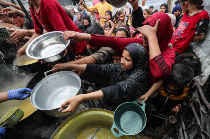 Palestinians receive food cooked by a charity kitchen, in Beit Lahia