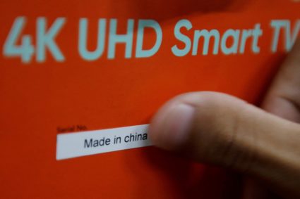 FILE PHOTO: An employee pastes a "Made in China" sticker on the box of a smart television at a television factory in Shenzhen