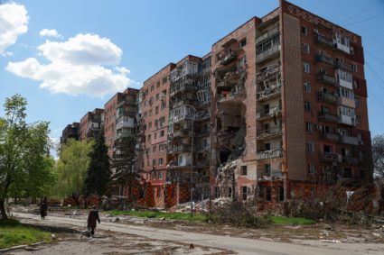 Residents walk next to an apartment building hit by Russian military strikes in the front line town of Pokrovsk