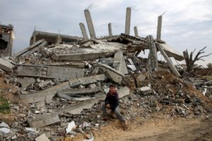 Palestinian boy Nezar Abdel Ghafour, who was injured due to an ordnance explosion, poses in front of the rubble of a destr...