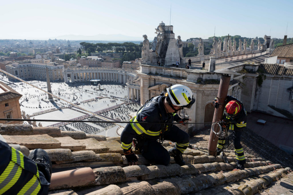 Firefighters install a chimney on the roof of the Sistine Chapel, ahead of the conclave