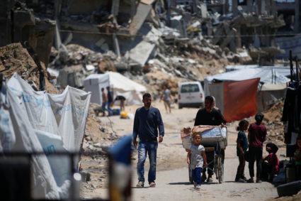 Palestinians walk near rubble of houses in Jabalia refugee camp