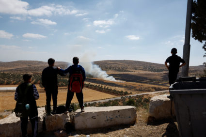 Palestinians watch a burnt farm, after an Israeli settlers attack in Al Mughayyir near Ramallah