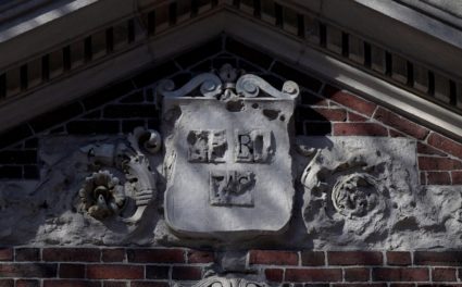 The Harvard University shield "VERITAS" sits above a campus entrance gate at Harvard University in Cambridge, Massachusetts