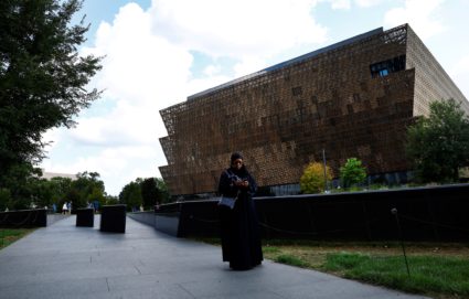 A woman stands in front of National Museum of African American History and Culture in Washington