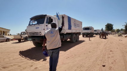 A staff member gestures at World Food Program (WFP) trucks transporting food and nutrition supplies from Chad to ZamZam Ca...