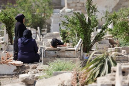 People visit the graves of their relatives at a cemetery, on the first day of the Muslim holiday of Eid al-Adha, in Damascus