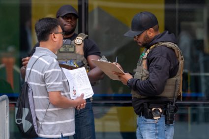 An ICE agent questions and documents the information of a person attempting to enter the U.S. Immigration Court, in Manhattan