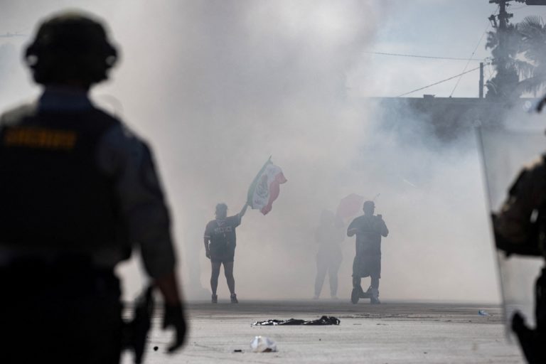 Protesters are blanketed in smoke along Alondra Boulevard during a standoff with law enforcement in Compton