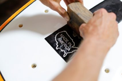 Steen Grams applies a "Made in America " logo to a surfboard at the INT surfboard factory in Carlsbad, California