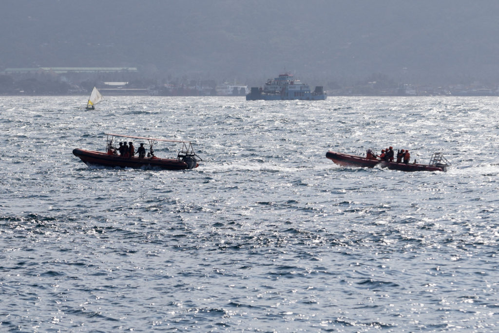 Indonesia rescue team members sail on dinghies during a search operation for missing passengers, after a ferry carrying 65...