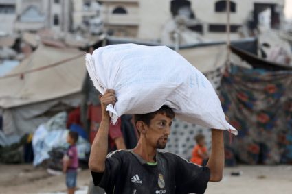 Palestinians gather to collect aid after trucks loaded with aid entered from Israel through central Gaza, in Gaza City