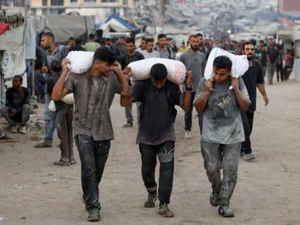 Palestinians gather to collect aid after trucks loaded with aid entered from Israel through central Gaza, in Gaza City