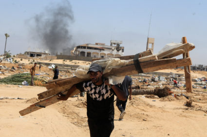 Displaced Palestinians inspect shelters damaged during an Israeli military operation in Deir Al-Balah