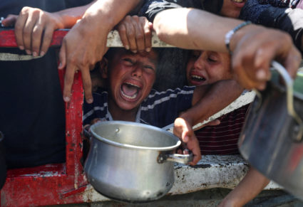Palestinians wait to receive food from a charity kitchen, in Gaza City