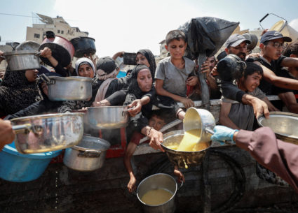 Palestinians wait to receive food from a charity kitchen, in Gaza City