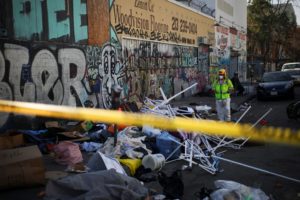 A worker stands on a corner during a street cleaning operation in Skid Row Los Angeles