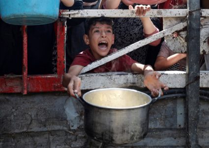 Palestinians wait to receive food from a charity kitchen, in Gaza City