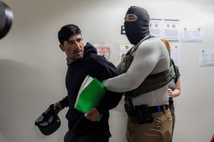 A migrant is detained by federal immigration officers at U.S. immigration court