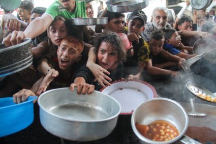 FILE PHOTO: Palestinians gather to receive food cooked by a charity kitchen, amid the Israel-Hamas conflict, in the northe...