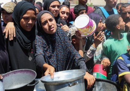 Palestinians gather to receive food from a charity kitchen, amid a hunger crisis, in Nuseirat
