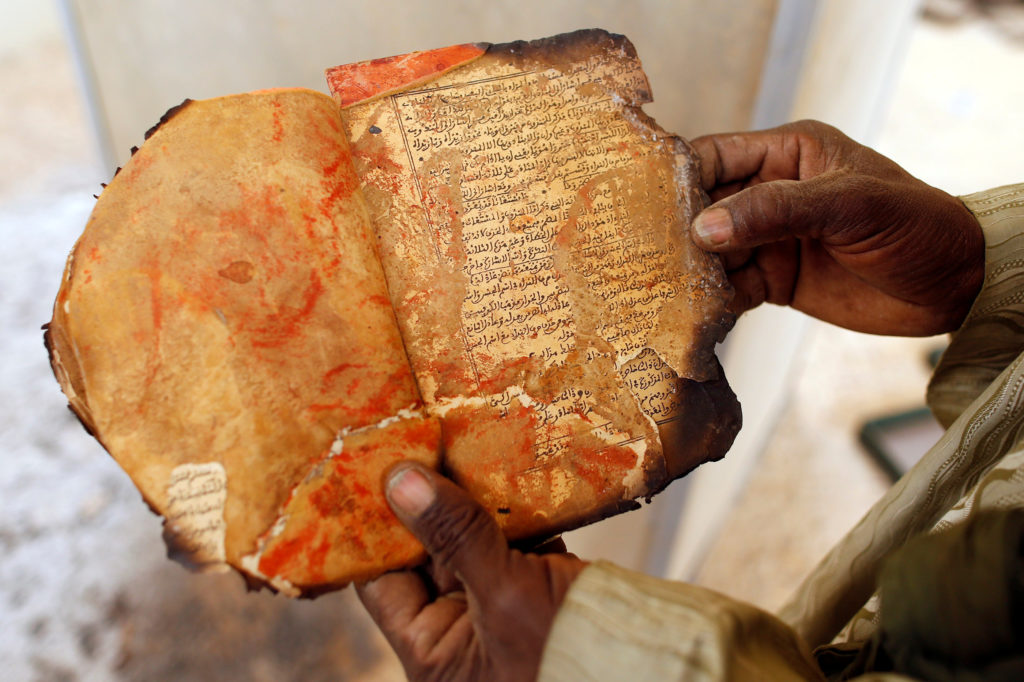 A museum guard displays a burnt ancient manuscript at the Ahmed Baba Institute in Timbuktu
