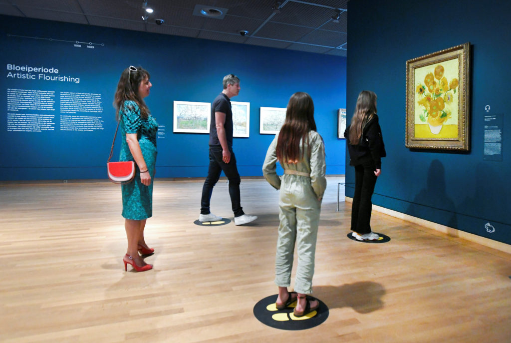 People look at Vincent van Gogh's Sunflowers painting at the Van Gogh Museum that reopened as Netherlands eases some of th...