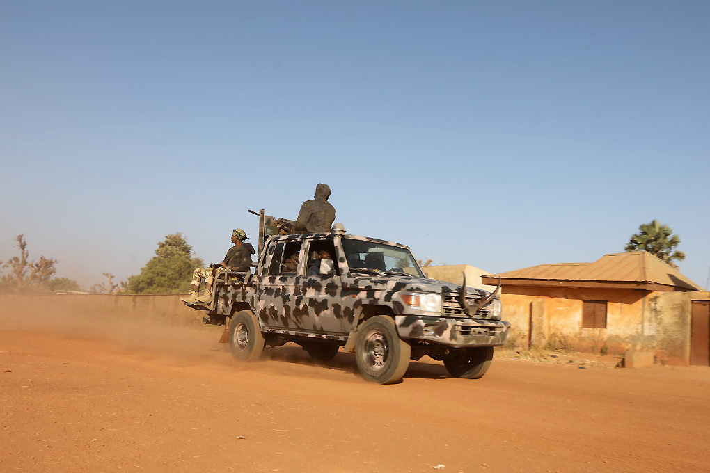 Members of security forces ride a truck as they patrol in Kankara