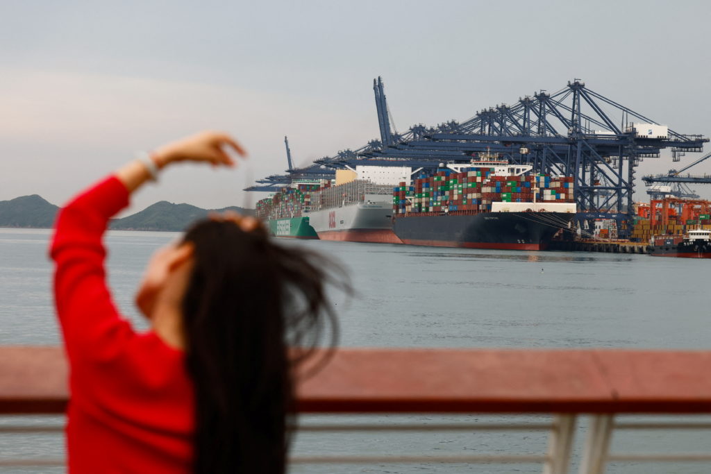 A woman arranges her hair as she sits near Yantian port in Shenzhen, Guangdong