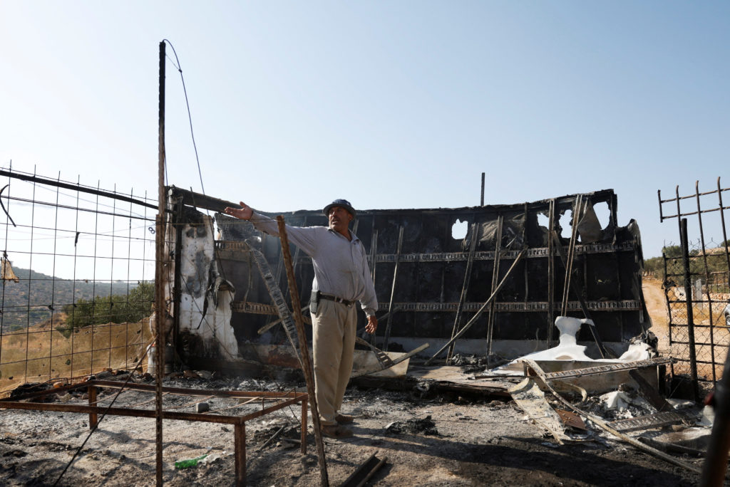 A Palestinian gestures while inspecting a structure that he says was burned by Israeli settlers in the Palestinian town of...