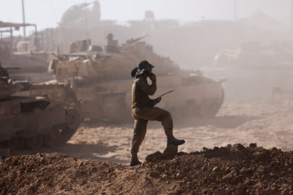 An Israeli soldier stands next to military vehicles as seen from the Israeli side of the Israel-Gaza border
